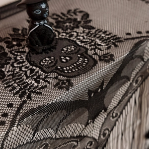 Close-up of black lace Halloween table runner with skull and bat patterns and tassels