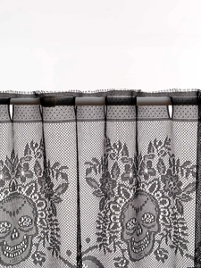 Close-up of black lace curtain with gothic skull patterns and rod pocket detail