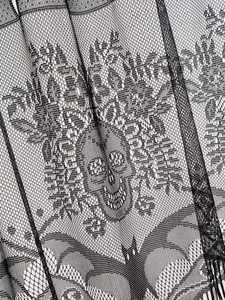 Close-up detail of Halloween black lace fabric with woven skull and bat patterns