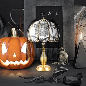 Lampe d'Halloween gothique avec socle doré et dentelle noire sur abat-jour à crânes