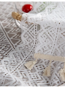 Close-up of geometric hollow knit table runner with delicate tassels and fringe detail