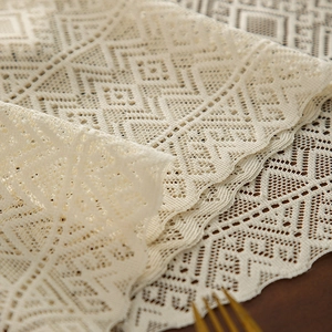 Boho cream crochet table runner with hollow geometric patterns on dark wood table