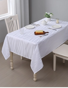 Detail of white striped jacquard tablecloth with abstract patterns on a wooden table