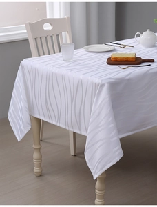 Detail of white jacquard tablecloth showing elegant wavy texture and fabric drape on table