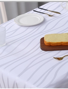 Detailed close-up of white striped jacquard tablecloth with wave texture and dinnerware