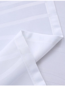 Macro shot of white striped jacquard tablecloth fabric showing texture and hem details