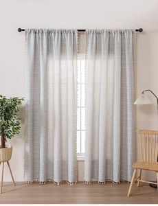 Detail of light gray plaid cotton linen curtain featuring delicate cream tassel fringe trim