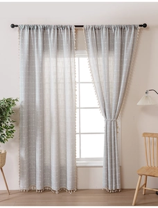 Detail of grey plaid cotton linen curtains with beige tassel edges in a modern room