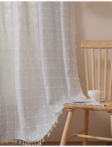 Detail of grey striped cotton linen curtain with elegant beige tassels on wooden chair