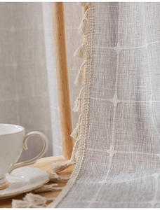 Detail of beige cotton linen curtain with star embroidery and decorative tassels
