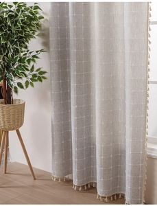 Detail of light gray linen curtains with white checkered pattern and fringe tassels