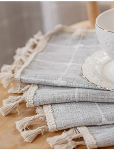 Close-up of grey and white checkered linen fabric with delicate cotton tassels