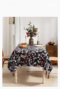 Detailed close-up of dark floral tablecloth featuring bird and berry prints on dining table
