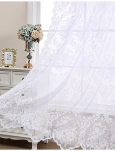 Gros plan d'un rideau en dentelle blanche avec motifs floraux et bords festonnés
