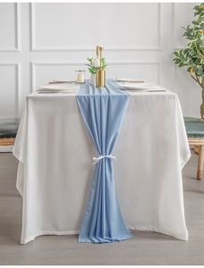 Close-up of light blue table runner with elegant ribbon knots and soft flowing fabric