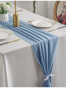 Detail of light blue wrinkled table runner with elegant white ribbon tie on tablecloth