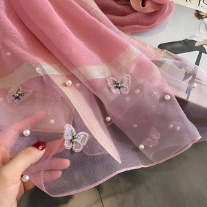 Gros plan d'une écharpe en soie rose avec broderie papillon 3D et détails en perles