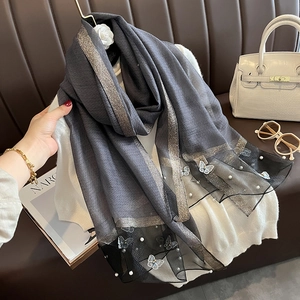 Détail d'un foulard en soie gris foncé avec broderie papillon blanche et perles