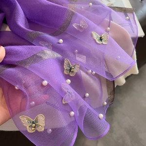 Détail d'une écharpe en tulle violet avec broderie papillon dorée et accents de perles