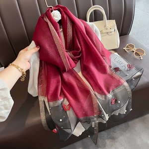 Détail d'un foulard en soie avec broderie papillon et finitions en perles fines