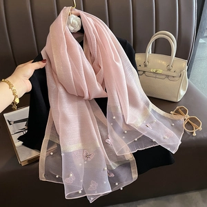 Détail d'une écharpe en soie rose avec broderie papillon, perles et rayures dorées