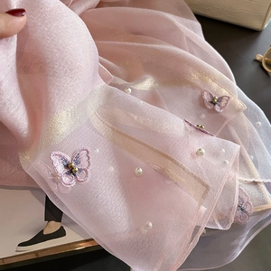 Détail d'un châle en soie rose avec broderie papillon 3D et accents de perles