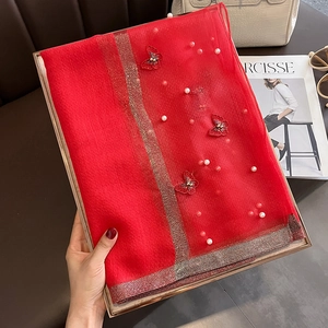 Détail d'une écharpe en maille rouge avec papillons 3D et perles blanches cousues