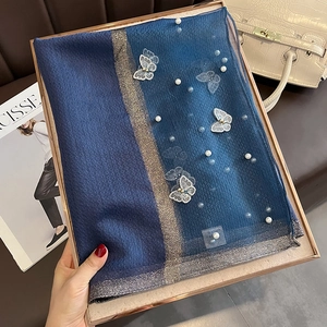 Détail d'une écharpe en soie avec broderies papillon et perles dans un coffret cadeau