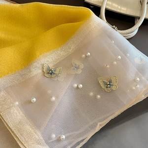 Détail de broderie papillon et perles sur écharpe en soie jaune avec bordure en organza