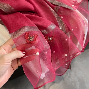 Détail de foulard en soie rouge avec broderie papillon et perles sur tissu transparent