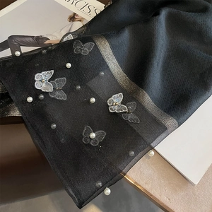 Détail d'une écharpe noire en soie avec broderies papillons et perles blanches élégantes