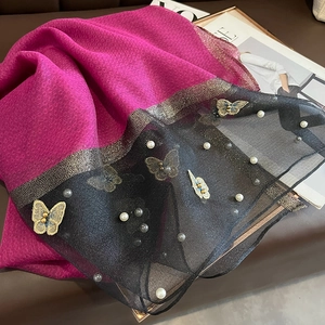 Détail d'une écharpe en soie fuchsia avec broderie papillon dorée et perles
