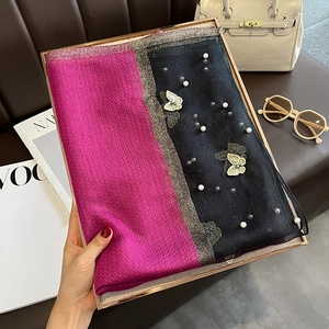 Détail d'une écharpe en soie rose et noire avec broderie papillon et perles blanches