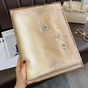 Détail d'une écharpe en soie avec perles blanches et broderie papillon 3D sur plateau