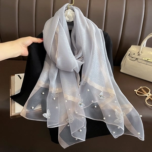 Détail d'une écharpe en soie gris clair avec broderie papillon blanche et perles décoratives