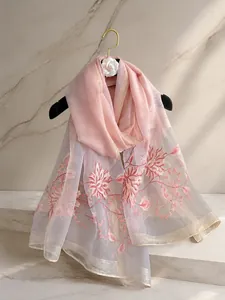 Detalle de bufanda de seda rosa con bordado floral y elegante ribete dorado
