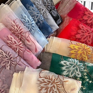 Gros plan détaillé de la broderie florale complexe sur un tissu léger en soie et laine