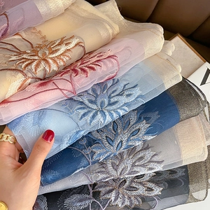 Gros plan d'écharpes en laine de soie avec broderie florale montrant texture et couleurs