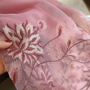 Détail macro de broderie florale rose sur tissu transparent en soie et laine