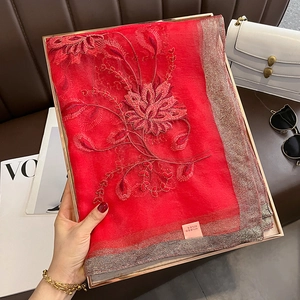 Détail d'une écharpe rouge en soie et laine avec paillettes et broderie florale