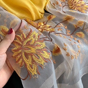 Détail d'une écharpe en soie et laine avec broderies florales dorées raffinées