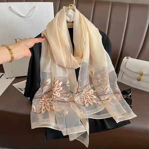 Détails de broderie sur écharpe en soie et laine avec motifs floraux beiges et marrons