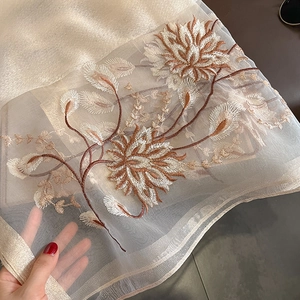 Gros plan sur écharpe en soie et laine champagne avec broderie florale et bords en satin