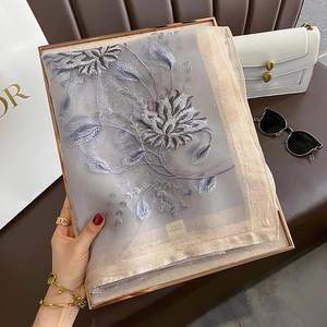 Détail d'une écharpe en résille grise avec broderie florale 3D et bordure dorée champagne