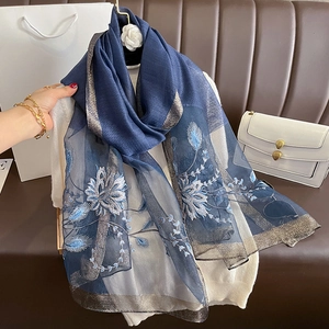 Détail d'une écharpe en soie et laine bleu foncé avec broderie florale et bords dorés