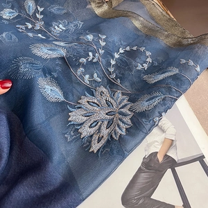 Détail de l'écharpe en soie et laine bleu foncé avec broderie florale et bordure dorée
