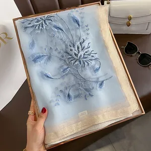 Détail d'une écharpe en soie et laine avec broderie florale bleue en coffret cadeau