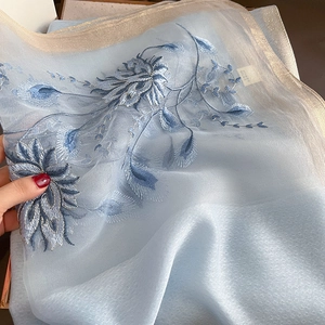 Vue détaillée d'une écharpe en soie bleu clair avec broderie florale et fil d'or