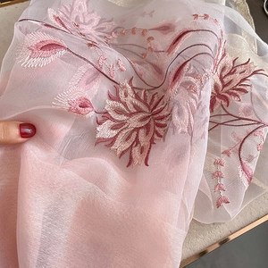 Détail d'une écharpe en soie et laine rose avec broderie florale et texture transparente