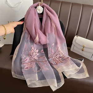 Broderie détaillée de motifs floraux violets sur une écharpe en soie et laine à bords dorés